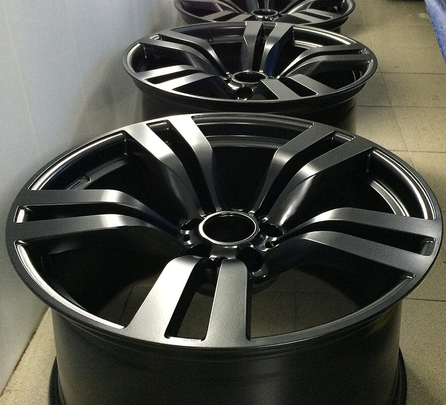 Black and machined alloy wheels with white accent stripes, displayed in showroom setting